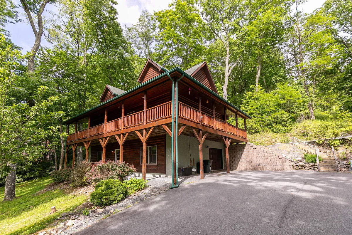 A peaceful view of the wooden porch and the surrounding greenery, emphasizing the spaciousness of the deck and the seamless flow from cabin to outdoors. The scene suggests a versatile space suited for gatherings, lounging, and savoring the mountain air.