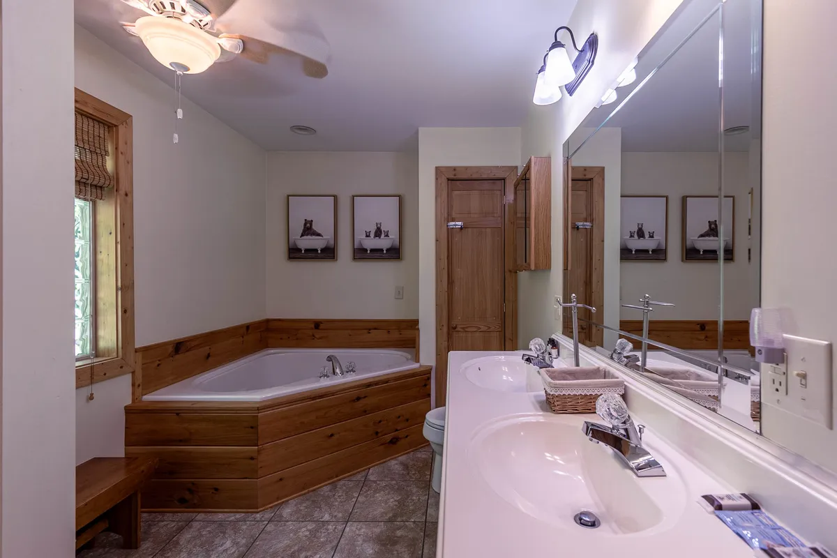 A luxurious bathroom featuring a spacious jacuzzi tub, double vanity, and rich wood accents, evoking a spa-like atmosphere. Framed artwork and subtle lighting enhance the sense of relaxation and self-care.